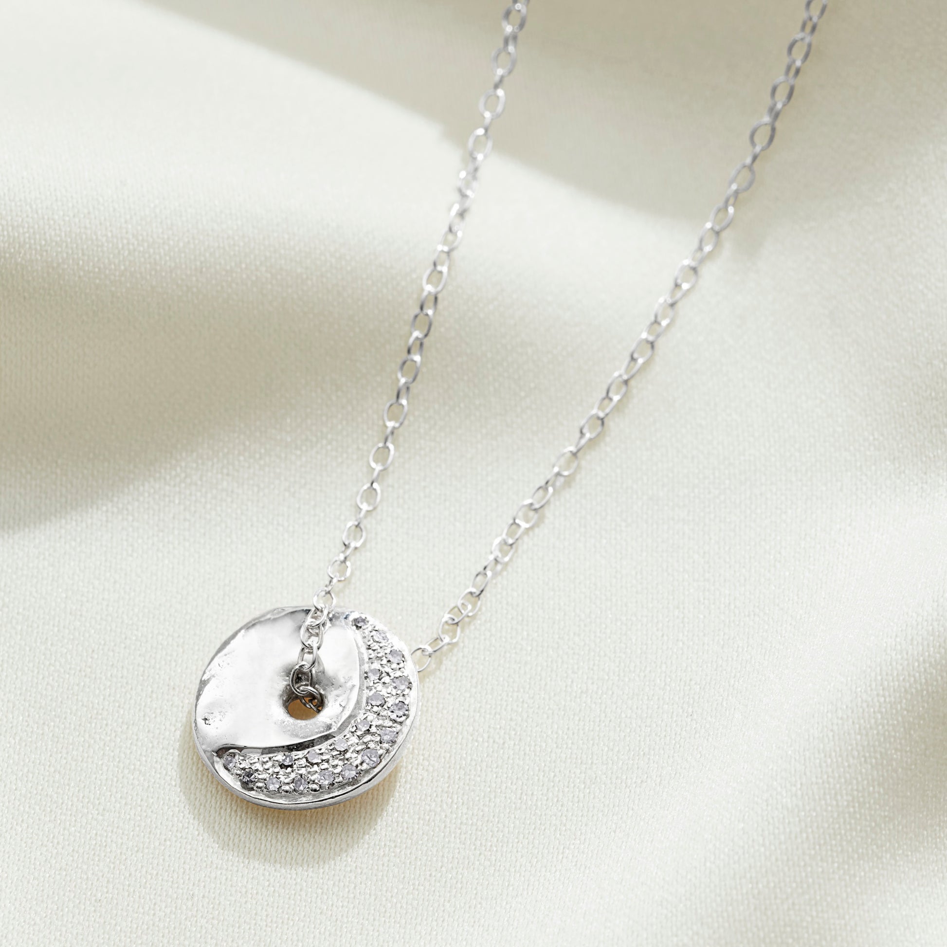 Waxing crescent moon phase silver necklace set with diamonds on a fine trace chain by Claudette Worters