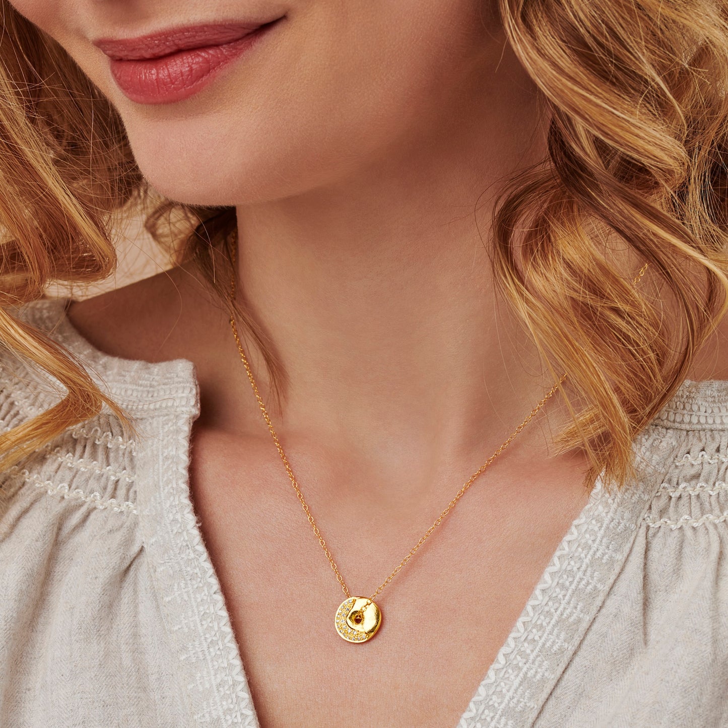 Close-up of a woman wearing a gold crescent moon necklace set with real diamonds by Claudette Worters