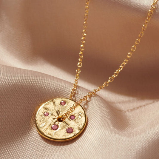 Gold coin disc pendant set with little faceted pink tourmaline birthstones hung on a delicate gold trace chain by Claudette Worters