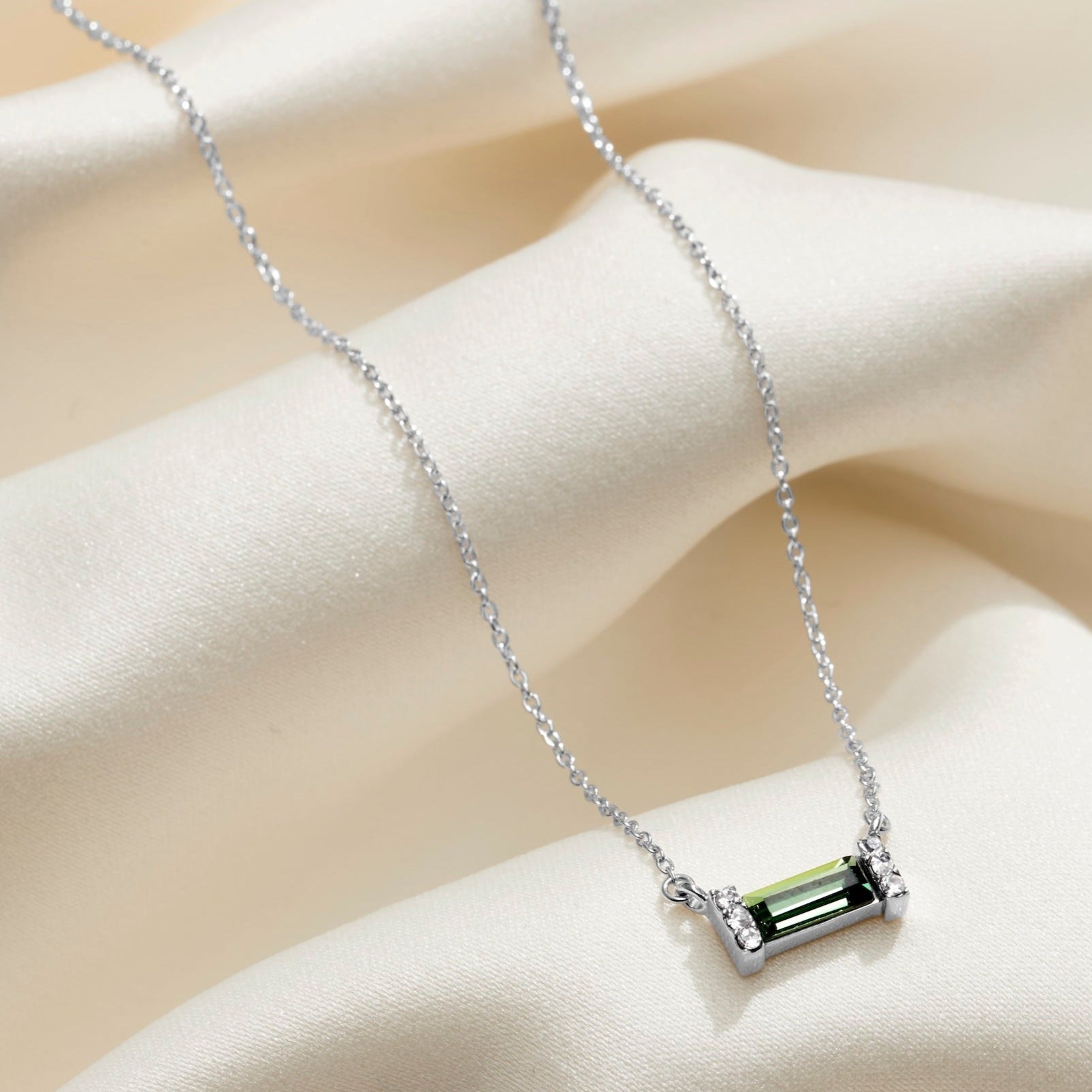 Sterling silver necklace with a dark green peridot baguette shaped crystal and pavé crystal stones on a delicate sterling silver trace chain.