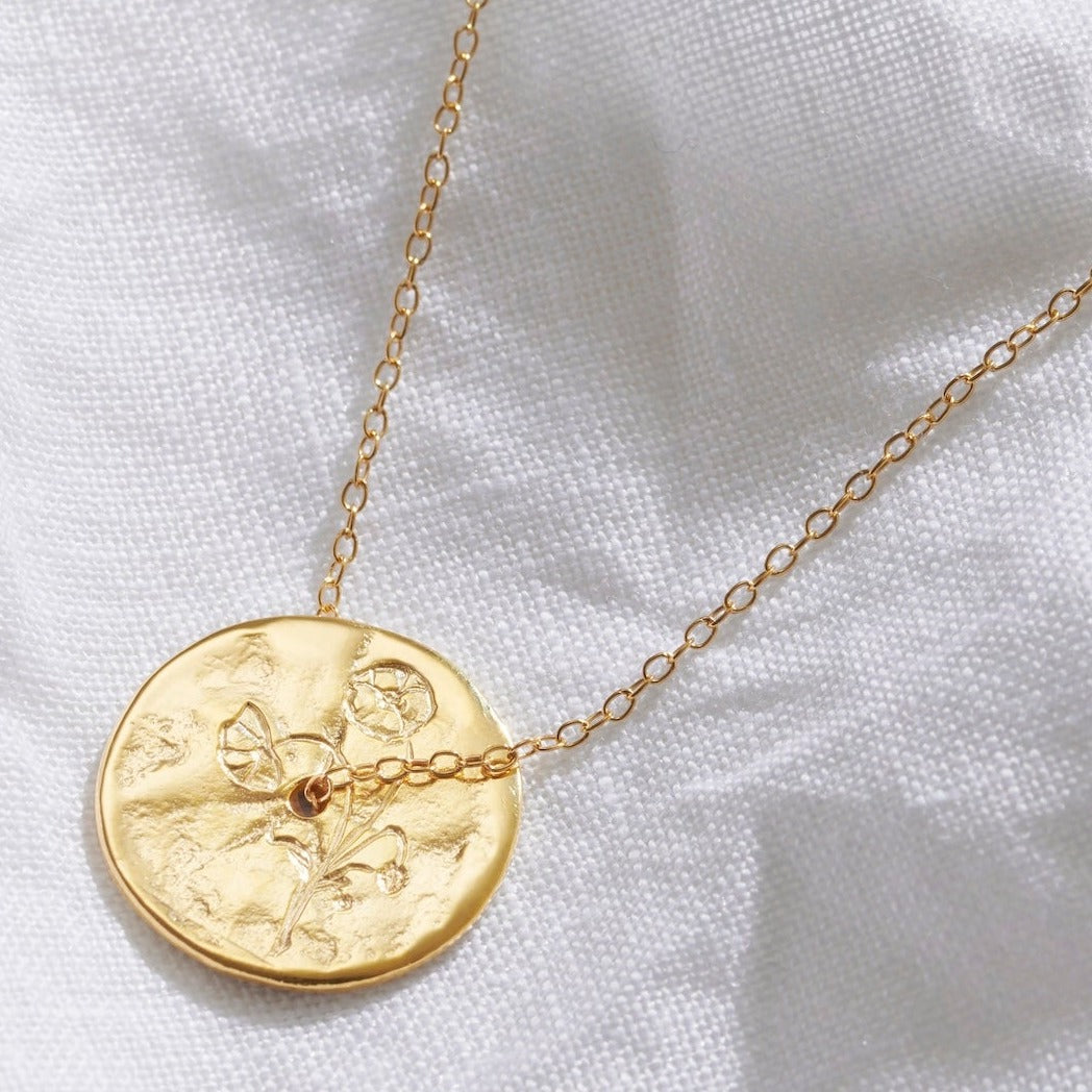 Birth flower gold coin pendant hand engraved with a Poppy blooms.  A dainty gold trace chain threads through the middle of the disc pendant.