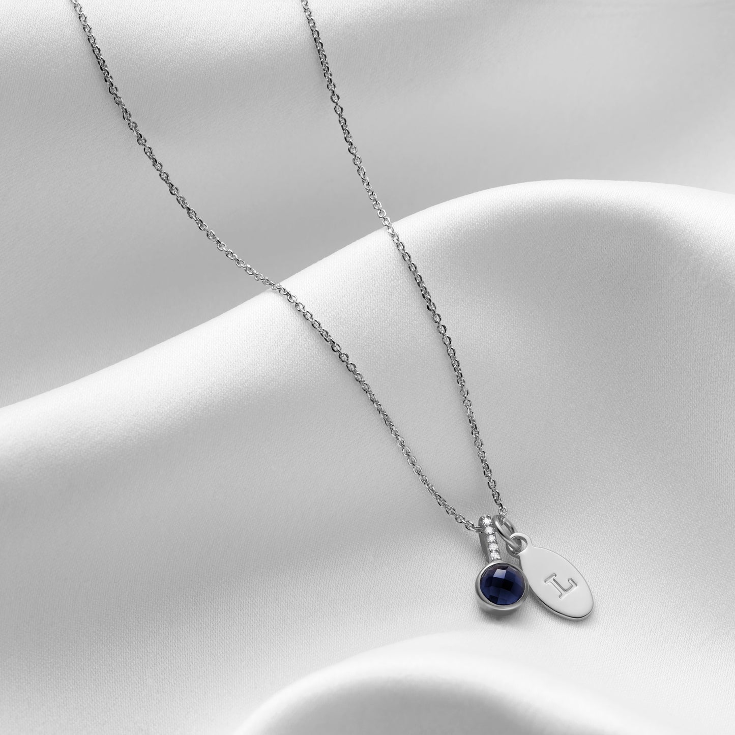 Sapphire and diamond pendant with oval initial charm by Claudette Worters