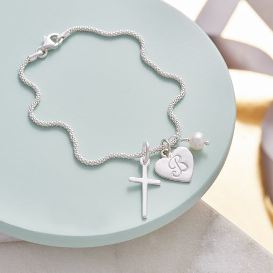 Cross charm bracelet in sterling silver with birthstone and initial charm by Claudette Worters