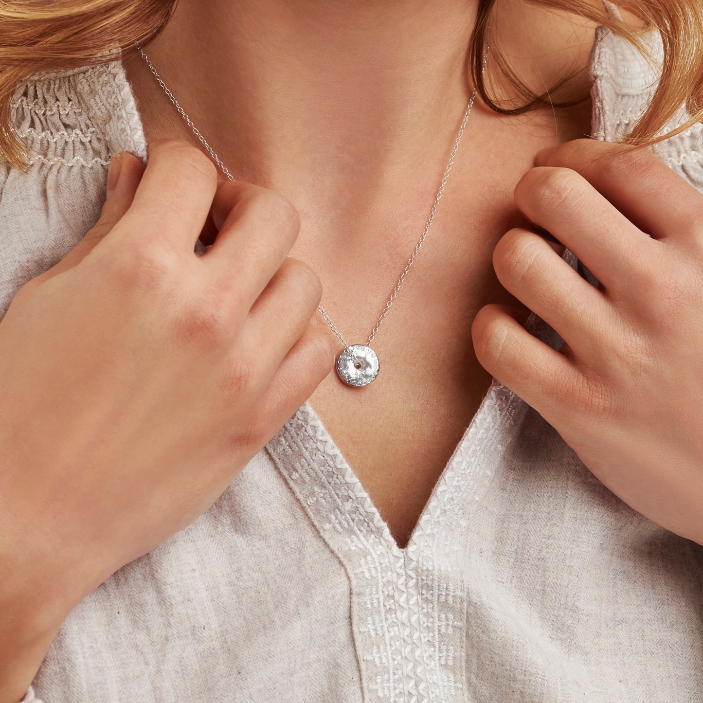 Silver disc necklace with lightly hammered surface with real diamonds around the edge to depict the full moon phase by Claudette Worters