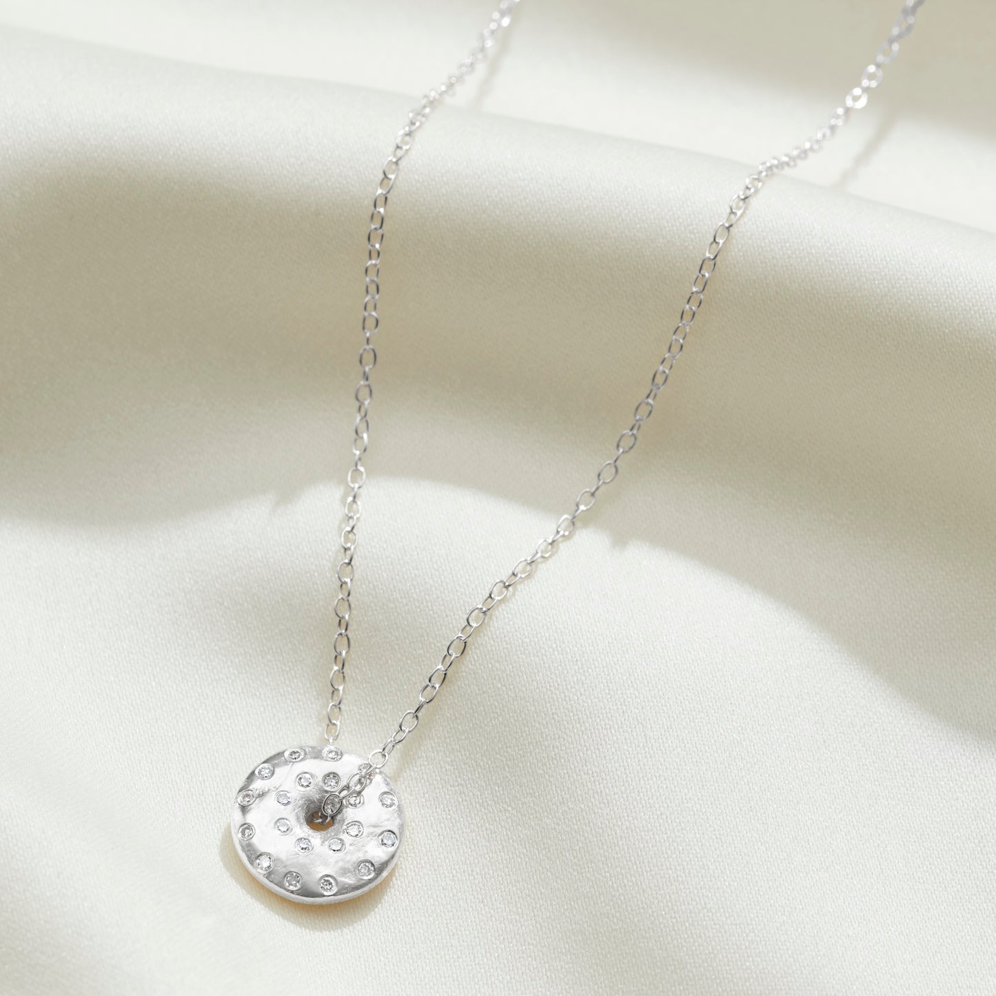 Moon phase necklace in sterling silver with diamonds depicting the full moon by Claudette Worters