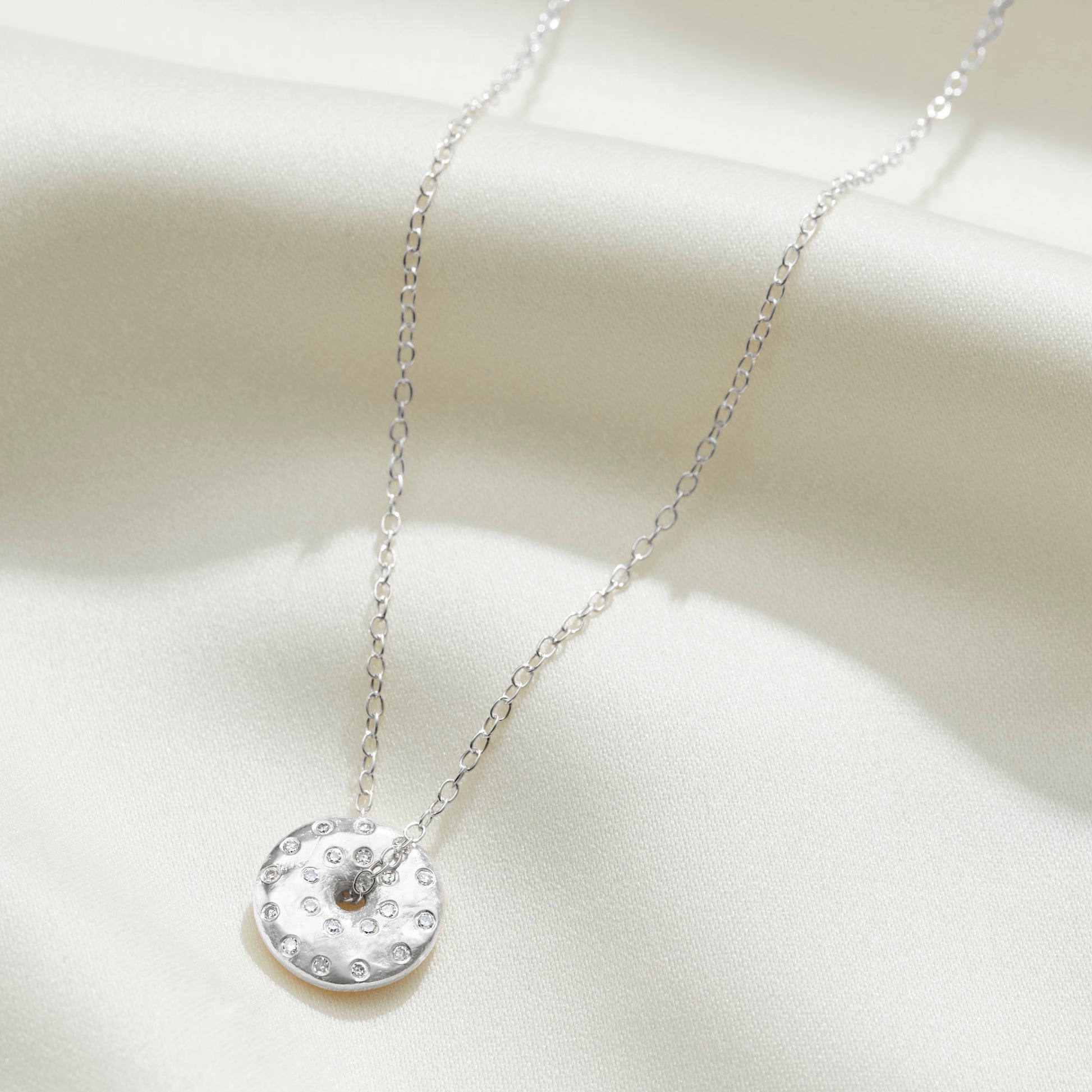 Moon phase necklace in sterling silver with diamonds depicting the full moon by Claudette Worters