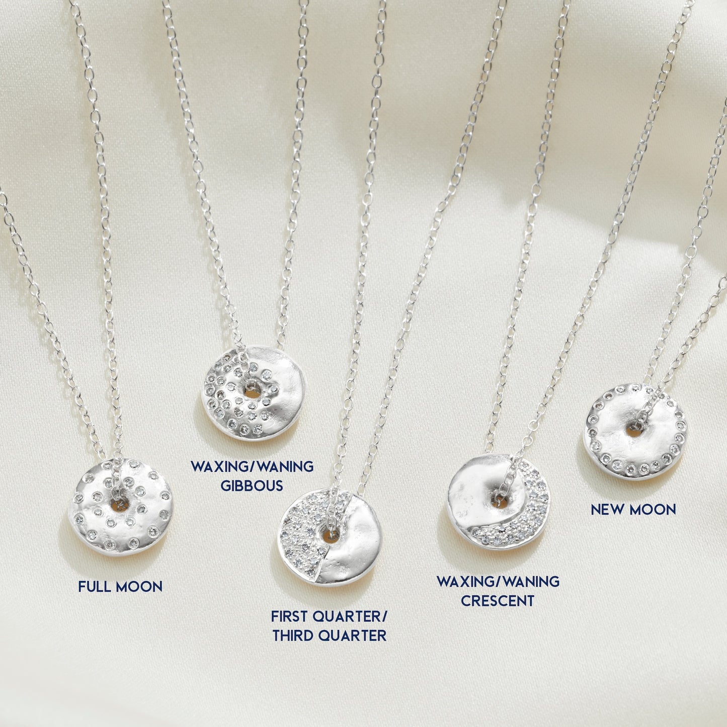 Silver necklaces with moon phase pendants set with genuine diamonds on a white background