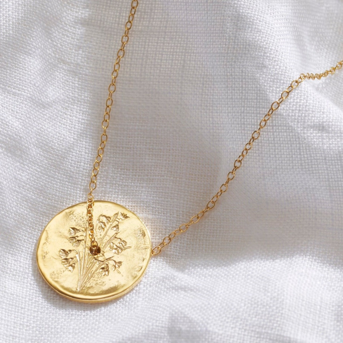 Spinner disc pendant in 18 carat yellow gold vermeil with hand engraved Snowdrop birth flowers.  A fine gold vermeil trace chain runs through the centre of the pendant.