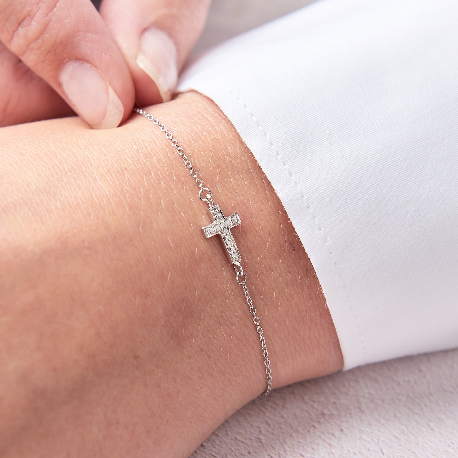 Sterling silver cross bracelet set with tiny white diamonds on a dainty sterling silver trace chain by Claudette Worters.