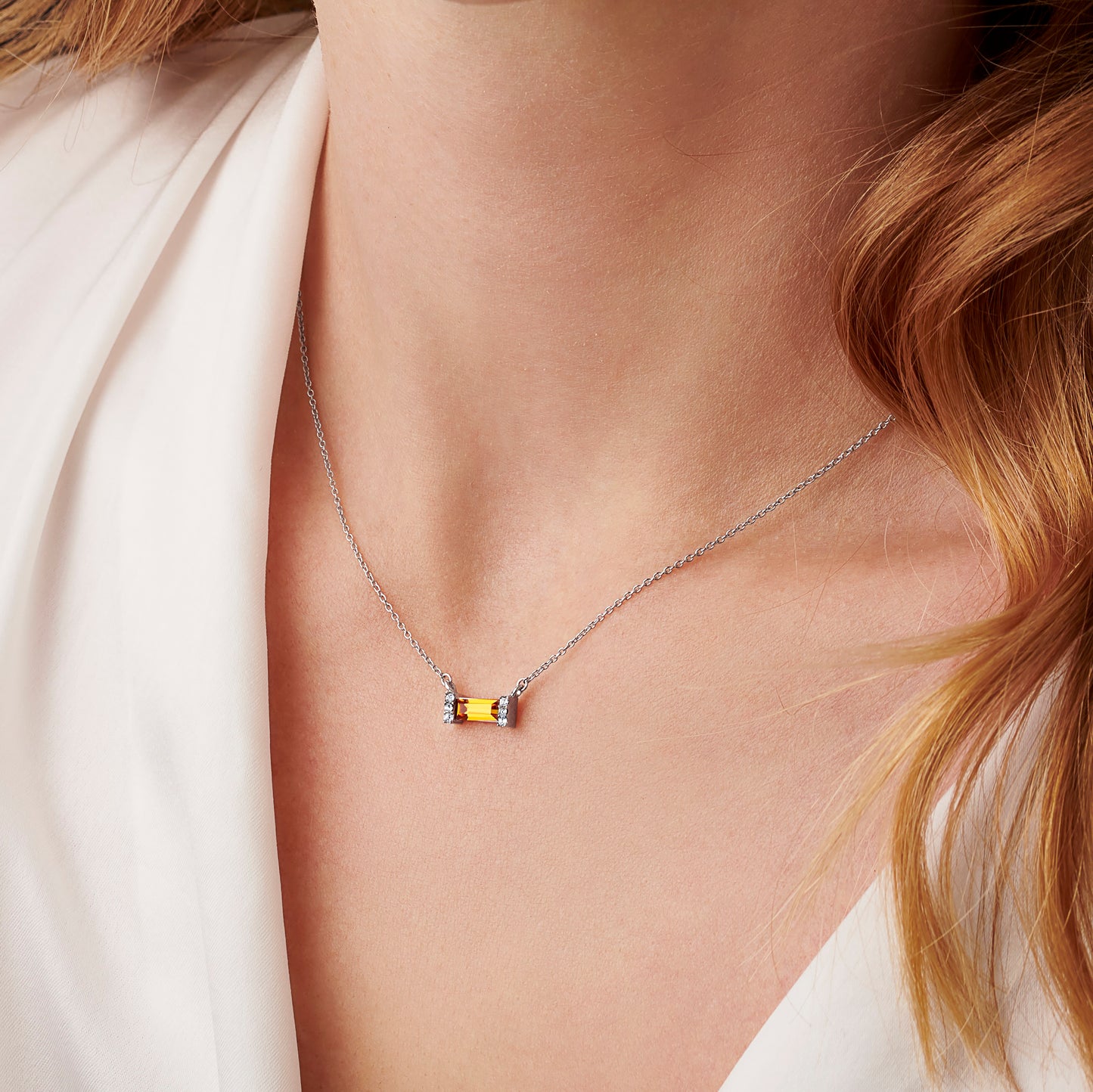 Woman wearing an orange topaz baguette shaped crystal necklace with pavé settings on a fine sterling silver trace chain. 