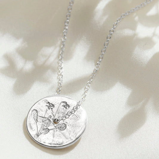 Solid silver circle disc pendant with hand engraved violet flowers on a fine sterling silver trace chain.