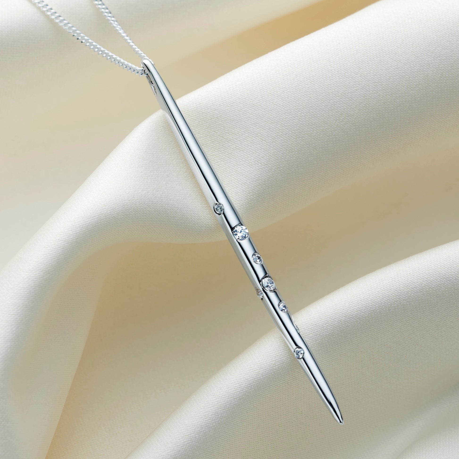 Close-up of highly polished sterling silver Virgo constellation necklace featuring a long, slender spike pendant hanging vertically with delicate star details, suspended on a fine sterling silver chain.